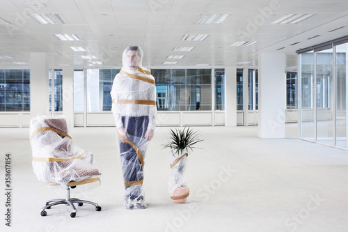 Businessman wrapped in bubble wrap in new office photo