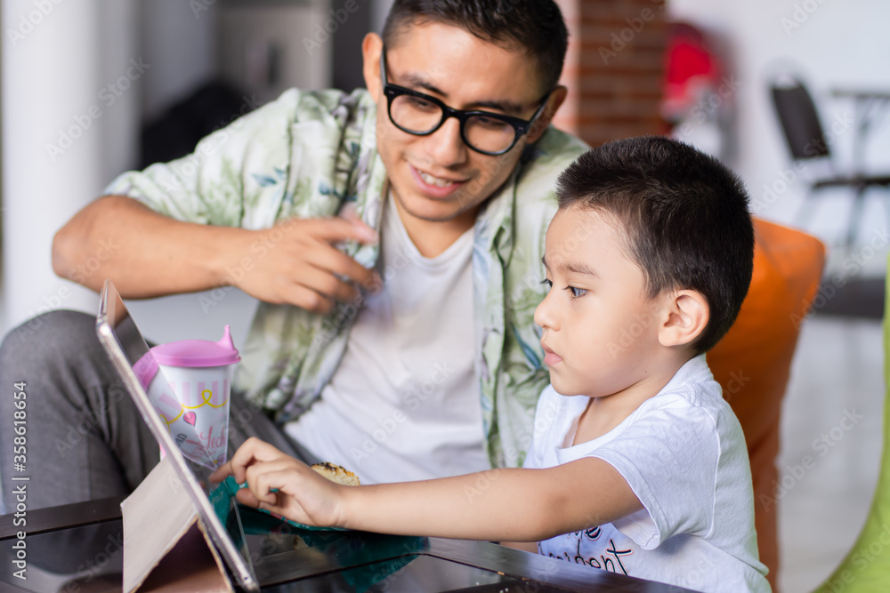 Obraz premium Young man and child watch a tablet at home