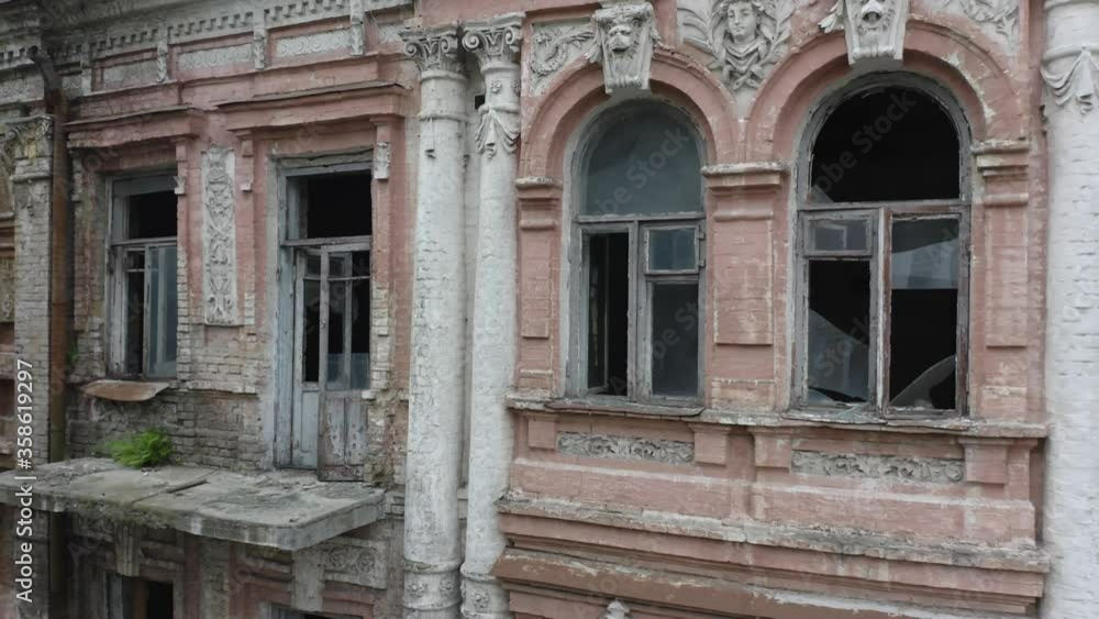 Broken windows of an abandoned old manor (mansion) house in the neoclassical style with an abundance of decor. Deserted building of the 19th century. Aerial side view. Close-up shot Broken windows of an abandoned old manor (mansion) house in the neoclassical style with an abundance of decor. Deserted building of the 19th century. Aerial side view. Close-up shot