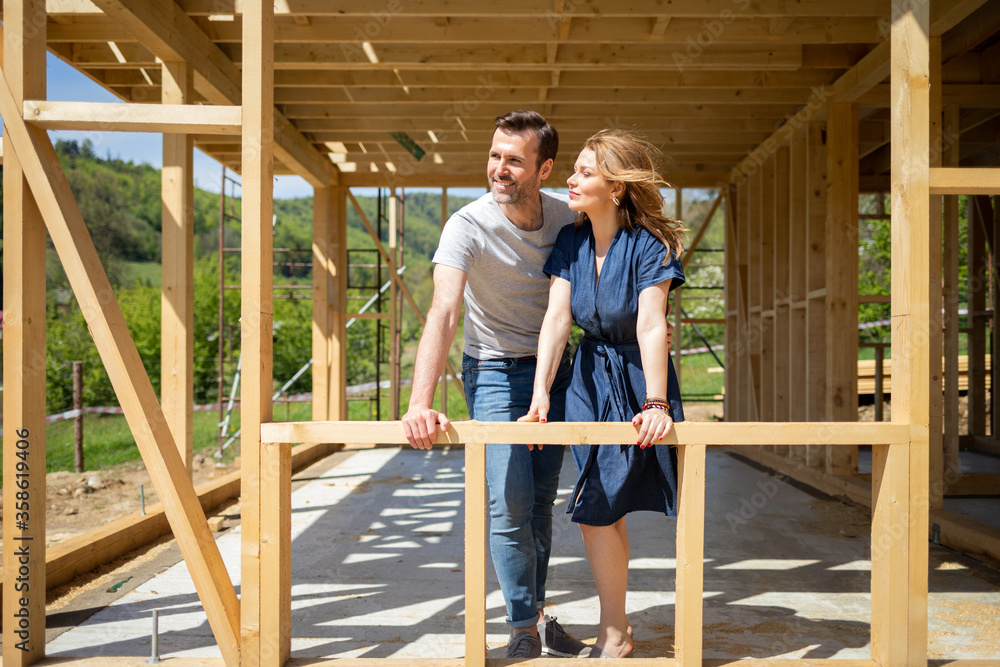 Couple standing on future window in construction site of their new house, dreams come true Couple standing on future window in construction site of their new house, dreams come true