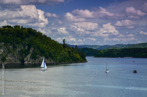 Fototapeta Naklejka Na Ścianę i Meble -  rock lake motor boat sailboat forest