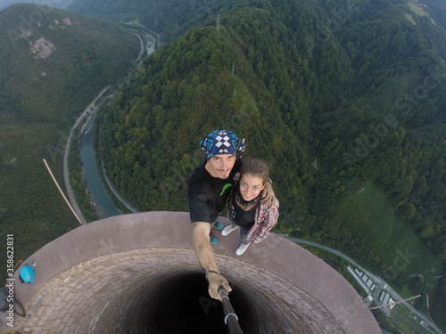Taking an extreme selfie on top of a ruined tower, life risking extreme sports, happy couple enjoying the panorama 