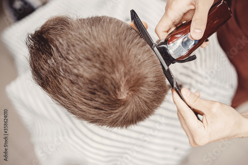 Hairdresser cuts hair men in barbershop. Barber doing correct trim electric shaver