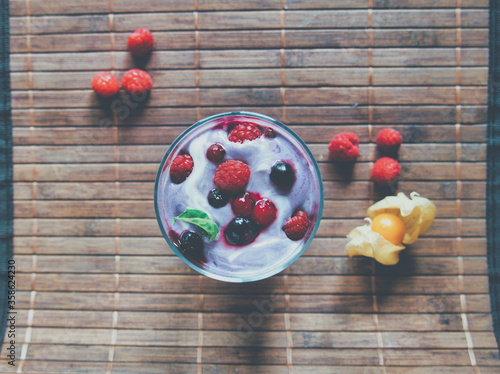 Joghurt, Dessert, Nachtisch im Glas mit Früchten, Beeren und einem Minzblatt