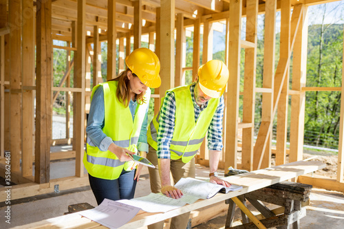 Fotografía Construction engineer and architect consult plans on building site of wood frami