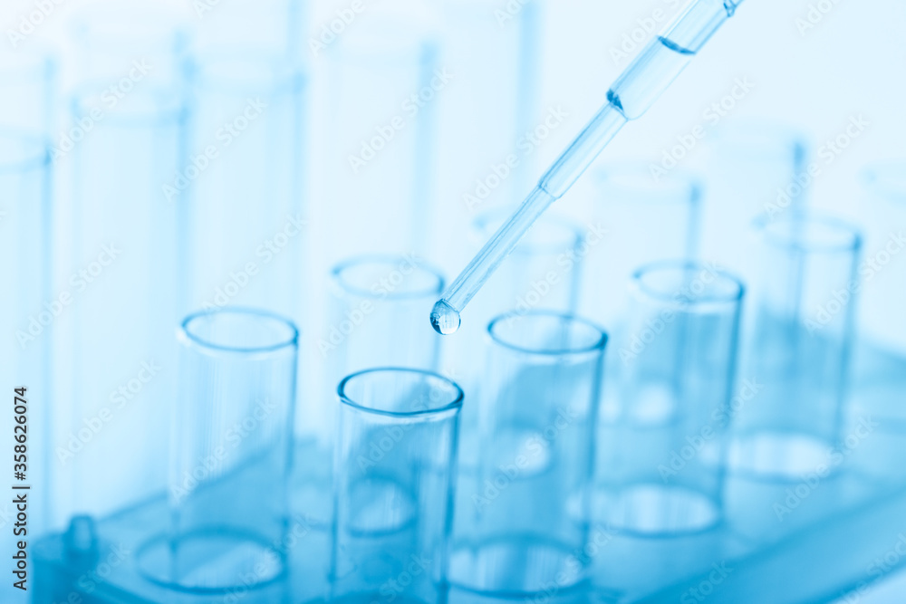 pipette with a drop and scientific laboratory test tubes in a research laboratory. pipette with a drop and scientific laboratory test tubes in a research laboratory.