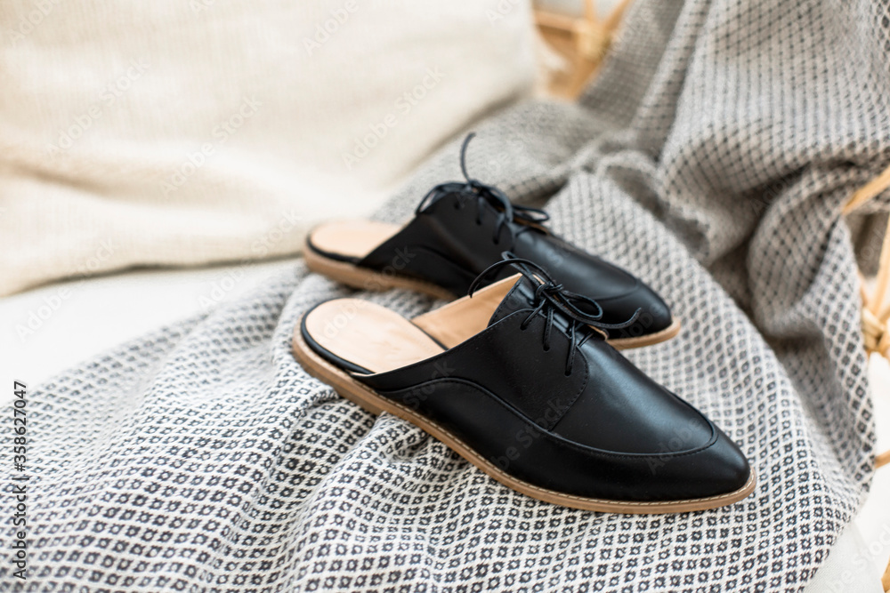 black leather shoes on female legs, a girl resting on a sofa in a blue skirt and with flowers in her hands black leather shoes on female legs, a girl resting on a sofa in a blue skirt and with flowers in her hands