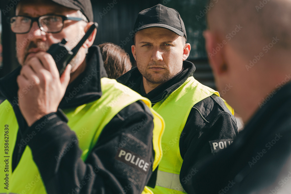 Proud policemen speaking on the walkie-talkie, reporting to station Proud policemen speaking on the walkie-talkie, reporting to station
