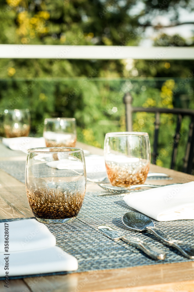 Outdoor table sitting including water glass, napkin and silver spoon fork