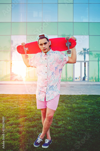 Foto Young teenager with his long board standing in park while resting after be ridde