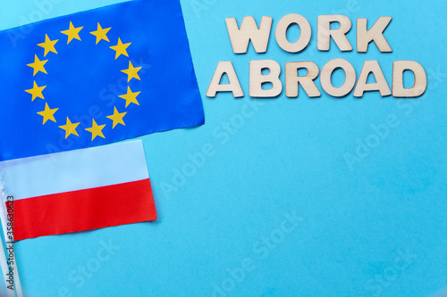 Search for employees, recruitment after crisis and coronavirus. work abroad-wooden letters on blue background. flatly with copy space. new hiring positions. EU and Polish flags, new hiring positions.