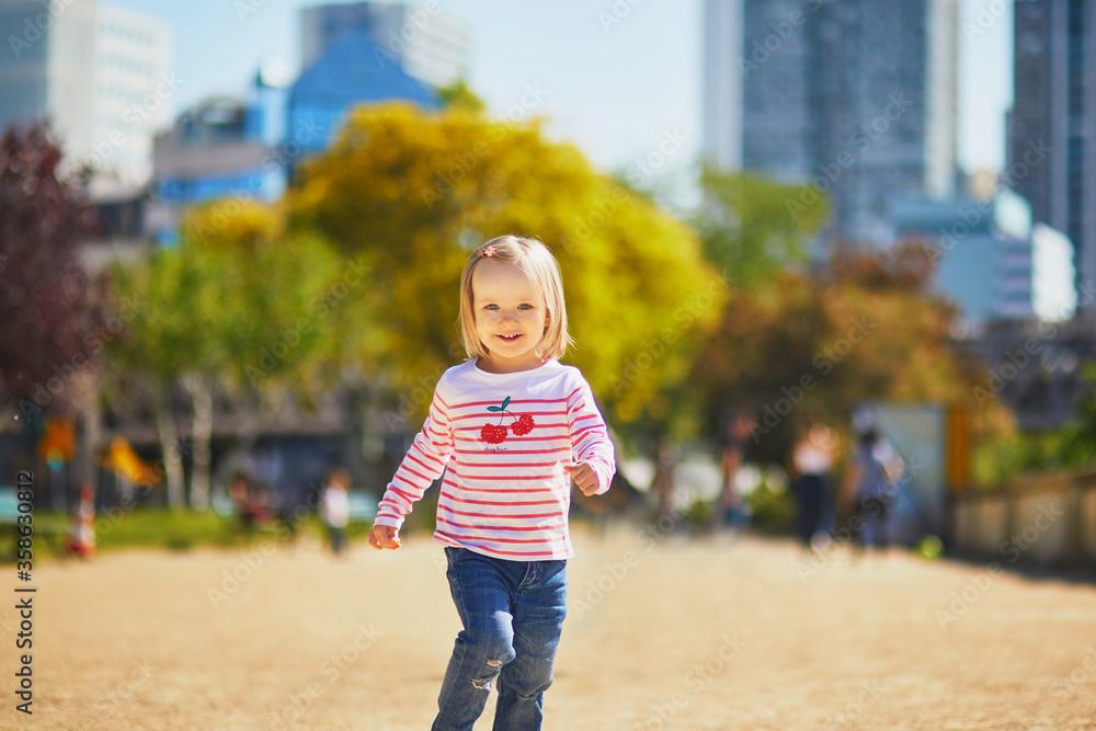 Fototapeta premium Cheerful toddler girl running on a street of Paris, France