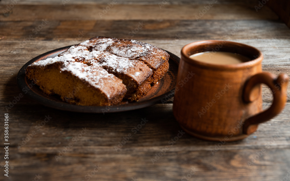 Coffee with milk in a ceramic mug, homemade cupcake in a ceramic bowl on a wooden table. Coffee with milk in a ceramic mug, homemade cupcake in a ceramic bowl on a wooden table.