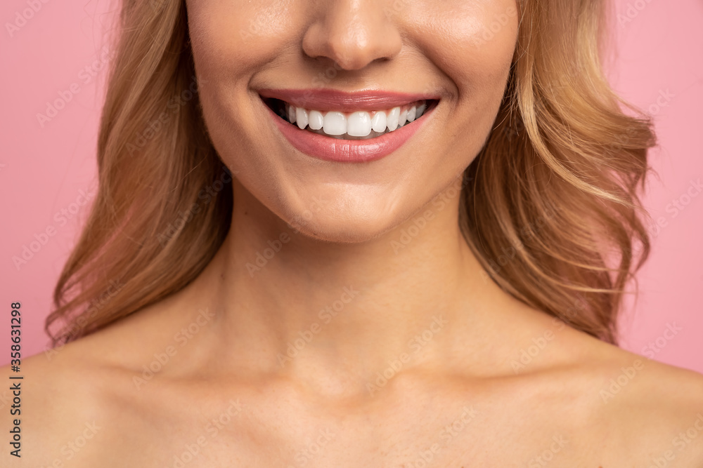 Close Up cropped half face portrait of attractive, nude, girl with healthy white teeth isolated on pink background, perfection, wellness, wellbeing, restoration concept Close Up cropped half face portrait of attractive, nude, girl with healthy white teeth isolated on pink background, perfection, wellness, wellbeing, restoration concept