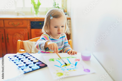 Adorable little girl painting with aquarelle
