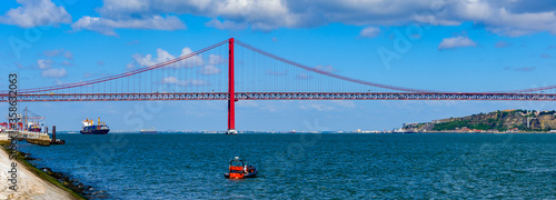 It's Yachts sailing near the Bridge 25 of April in Lisbon, Portugal. It was inaugurated on August 6, 1966