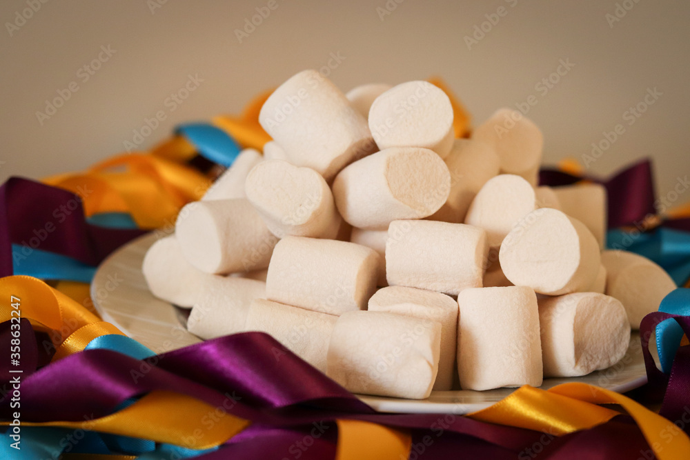 The white of the marshmallows contrast with the colors of the satin ribbons composing the decoration of a beautiful table. The white of the marshmallows contrast with the colors of the satin ribbons composing the decoration of a beautiful table.