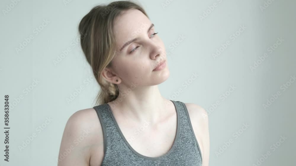 young girl in sportswear stretching neck on white background. slim female in activewear stretches before yoga class, fitness exercise, workout, dance lesson. morning routine, healthy lifestyle, warmup young girl in sportswear stretching neck on white background. slim female in activewear stretches before yoga class, fitness exercise, workout, dance lesson. morning routine, healthy lifestyle, warmup