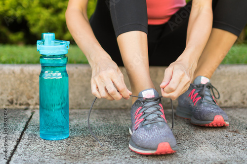 Runner tying shoe next to bottle of water. Drinking water and healthy active lifestyle concept. 