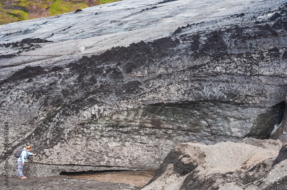 Fototapeta premium Woman feeling on the tongue of Myrdals Jokull Glacier near Skogar SW Iceland