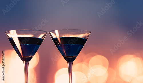 Two blue martini glasses on bar