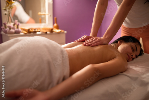 Young woman receiving massage in spa salon.