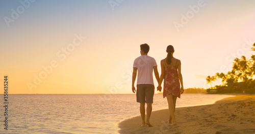 Man and woman holding hands walking on the beach at sunset. Travel  and leisure concept. 