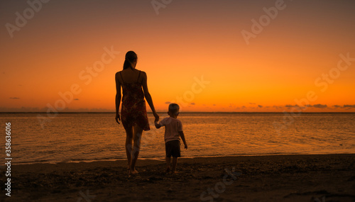 Mother and child walking down a beautiful beach holding hands. Parenting and childhood concepts. 