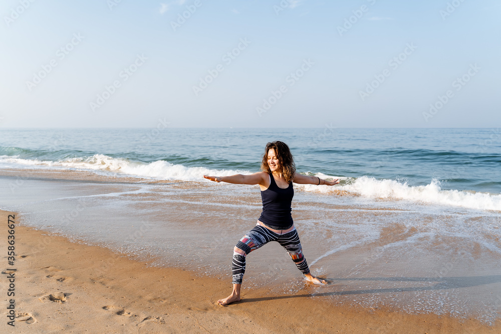 a young girl of European appearance does yoga on the beach early in the morning, practicing asana on the beach in India