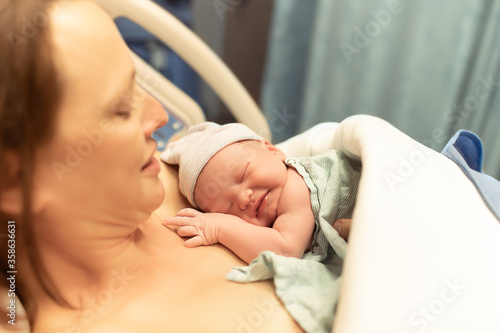 Mother and her newborn baby in hospital bed. Giving birth, and new life concept. 