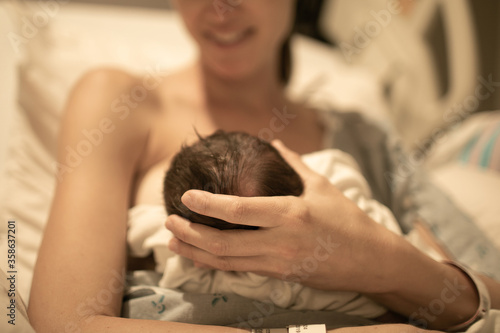 Mother in hospital bed feeding her newborn baby. 