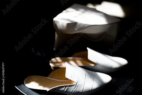 white shoes on a black background in the style for blogging, a finger indicates shoes, a hand shadow, a plate with an empty place for a price tag or inscription, casual leather shoes