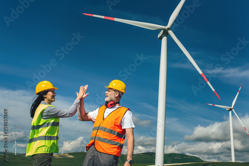 Windmill engineer giving high five, inspection and progress check wind turbine.