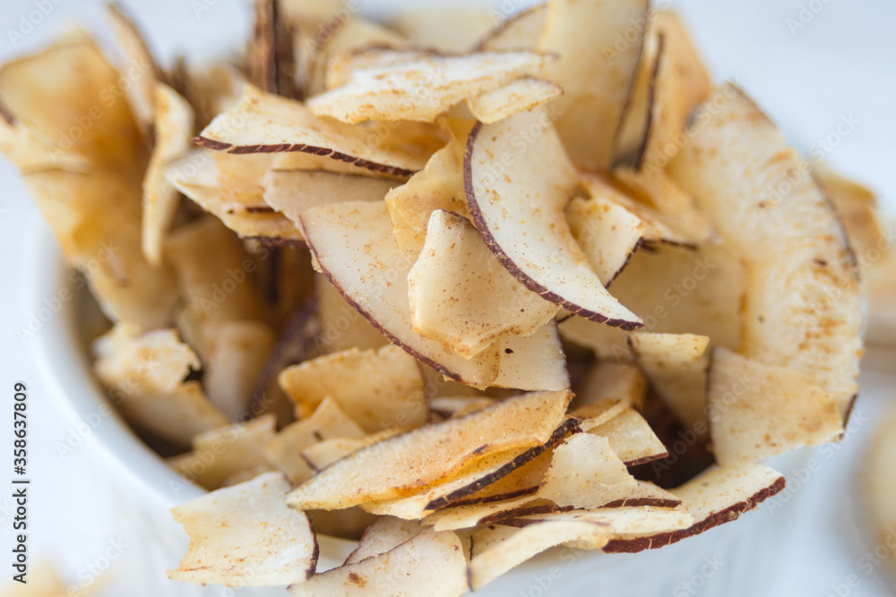 Delicious crispy coconut chips with salted caramel. Natural product made from coconut pulp. Useful snack for a snack. A closeup. Delicious crispy coconut chips with salted caramel. Natural product made from coconut pulp. Useful snack for a snack. A closeup.