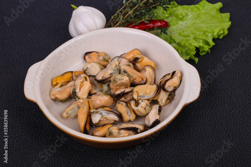 Pickled mussels in the bowl served pepper, garlic and salad