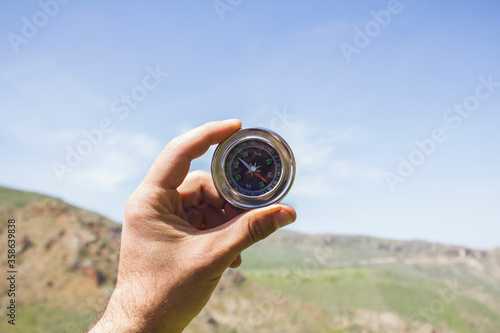 Holds the compass against the background of nature