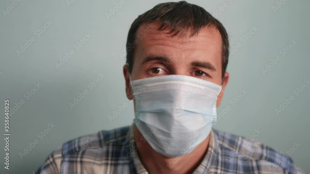 man wear puts on protective mask a indoor portrait. epidemic corona outbreak concept. male 37 years old brunette in blue medical mask isolated. Coronavirus disease. dad teamwork self-isolation in home man wear puts on protective mask a indoor portrait. epidemic corona outbreak concept. male 37 years old brunette in blue medical mask isolated. Coronavirus disease. dad teamwork self-isolation in home