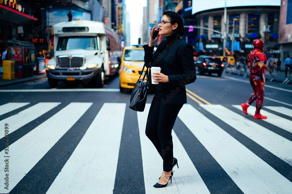 Confident female lawyer concentrated on phone talk while crossing street in new york city,professional businesswoman in formalwear having mobile conversation strolling on crosswalk with coffee to go.