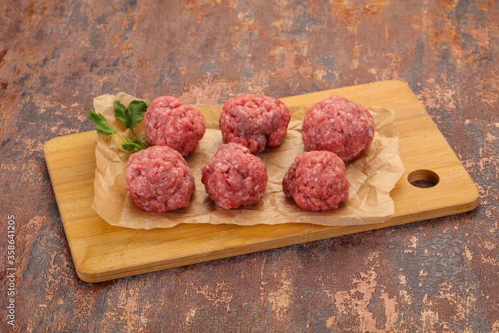 Raw meatball over wooden background Raw meatball over wooden background