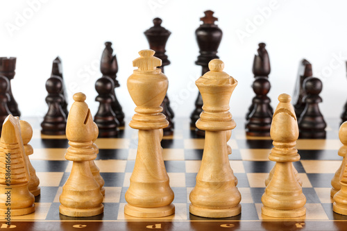 Wooden chess. Chess pieces arranged on a chessboard. Isolated on white background. Close-up
