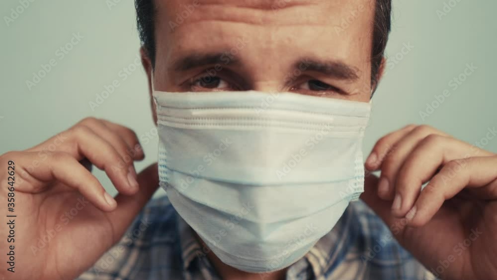 man wear puts on protective mask a indoor portrait. epidemic corona outbreak concept. male 37 years old brunette blue medical mask isolated. Coronavirus disease. dad teamwork self-isolation in home man wear puts on protective mask a indoor portrait. epidemic corona outbreak concept. male 37 years old brunette blue medical mask isolated. Coronavirus disease. dad teamwork self-isolation in home