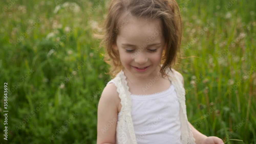 portrait of a child girl in a green field at sunset in summer portrait of a child girl in a green field at sunset in summer