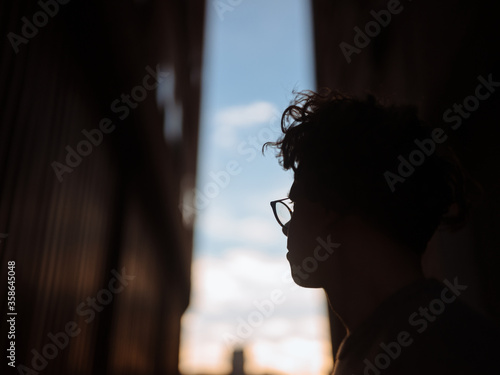 Silhouette of young guy framed between buildings looking out towards sky.