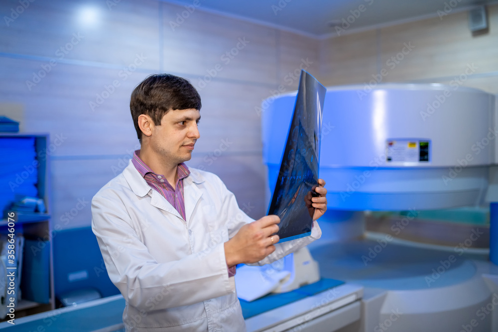 Mature male doctor looking at x-ray isolated on modern office backgound. Healthcare, roentgen, people and medicine concept. Mature male doctor looking at x-ray isolated on modern office backgound. Healthcare, roentgen, people and medicine concept.