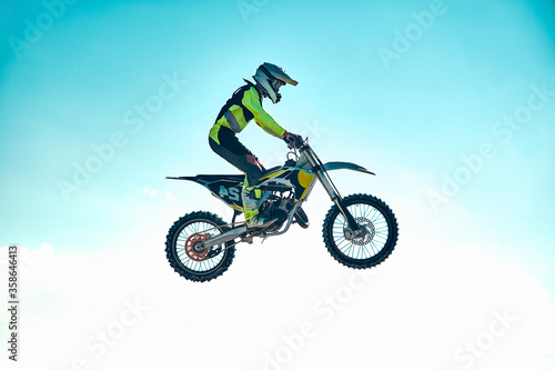 Fototapeta Naklejka Na Ścianę i Meble -  Extreme concept, challenge yourself. Extreme jump on a motorcycle on a background of blue sky with clouds. Copy space, all or nothing.