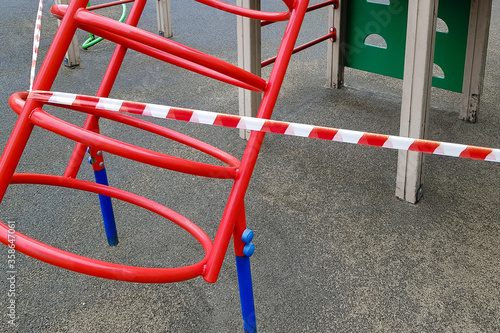 Children's sports metal structure on the playground wrapped with red barrier tape. Outside. Prohibition of outdoor walks, prevention of the coronavirus influenza virus covid-19. illness prevention.