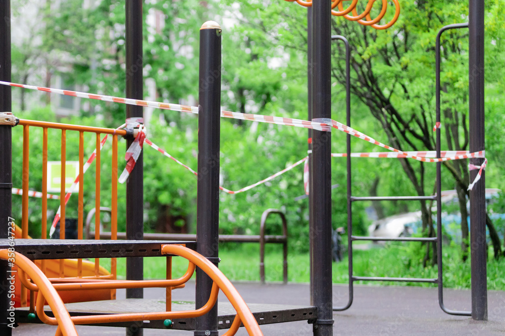 The play park of amusement and sports for young children is wrapped in red barrier tape. Outside. Prohibition of outdoor walks, prevention of the covid-19. moscow. selective focus