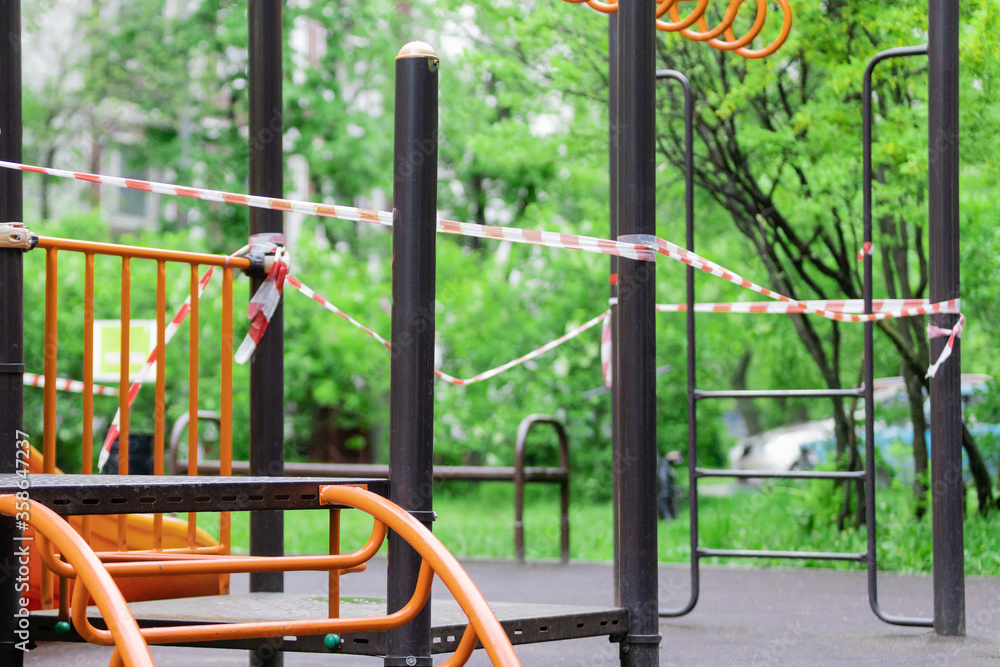 The play park of amusement and sports for young children is wrapped in red barrier tape. Outside. Prohibition of outdoor walks, prevention of the covid-19. moscow. selective focus The play park of amusement and sports for young children is wrapped in red barrier tape. Outside. Prohibition of outdoor walks, prevention of the covid-19. moscow. selective focus