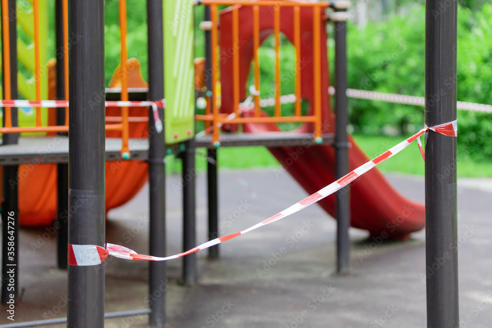 The play park of amusement and sports for young children is wrapped in red barrier tape. Prohibition of outdoor walks, prevention of the coronavirus influenza virus covid-19. lockdown. selective focus