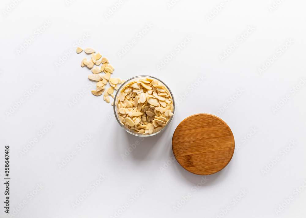 Almond flakes in a glass jar, wooden lid, white background Almond flakes in a glass jar, wooden lid, white background